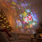 Salón de noche con árbol de Navidad y dibujos navideños de colores proyectados en la pared y el techo